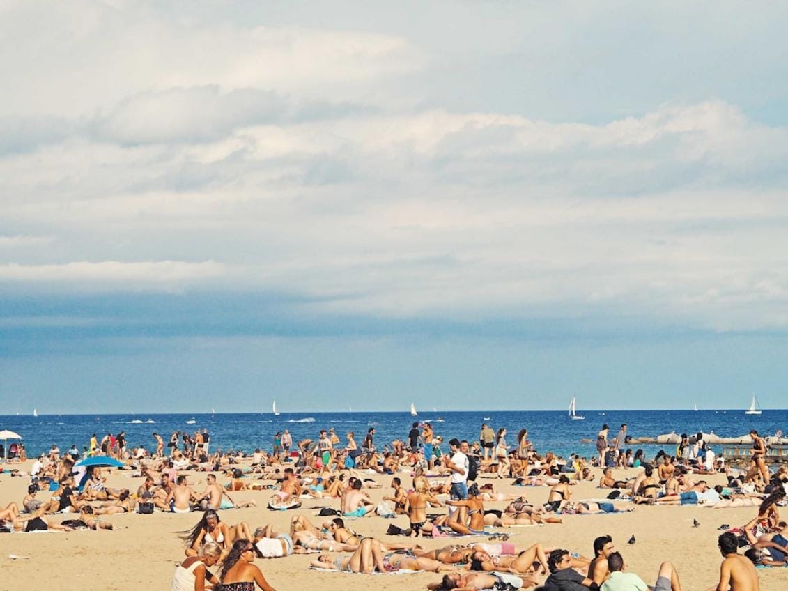 A lively beach scene in Konyaaltı with sunbathers, umbrellas, and clear blue waters