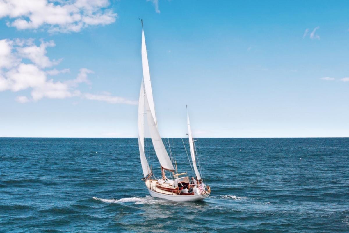 a sailboat gliding in clear blue waters near a lively Turkish resort town