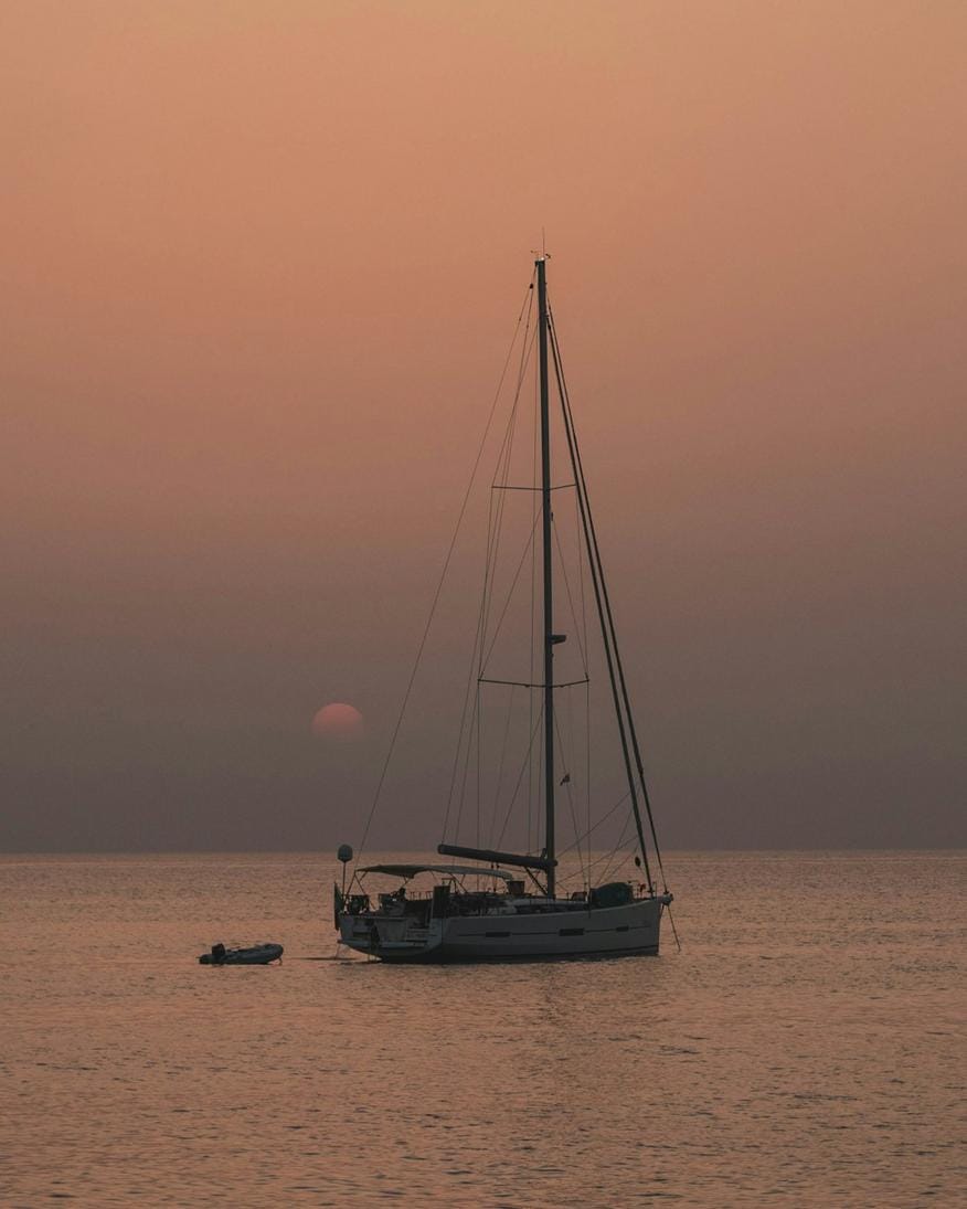 a boat sailing along a rugged coastline with crystal waters and green hills in the background